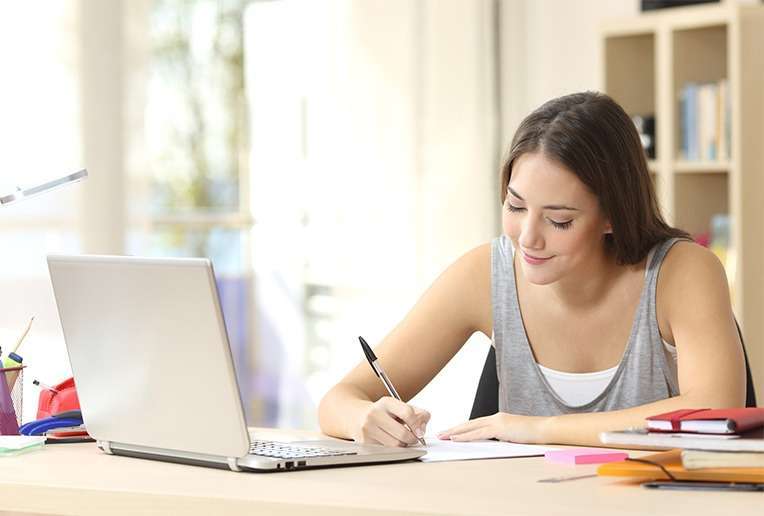 Young female student taking notes in online tutoring